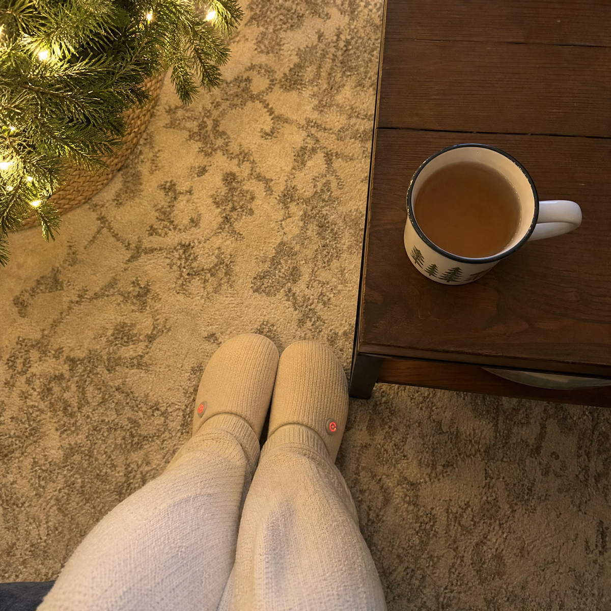 Feet in SnugToes slippers by the Christmas tree